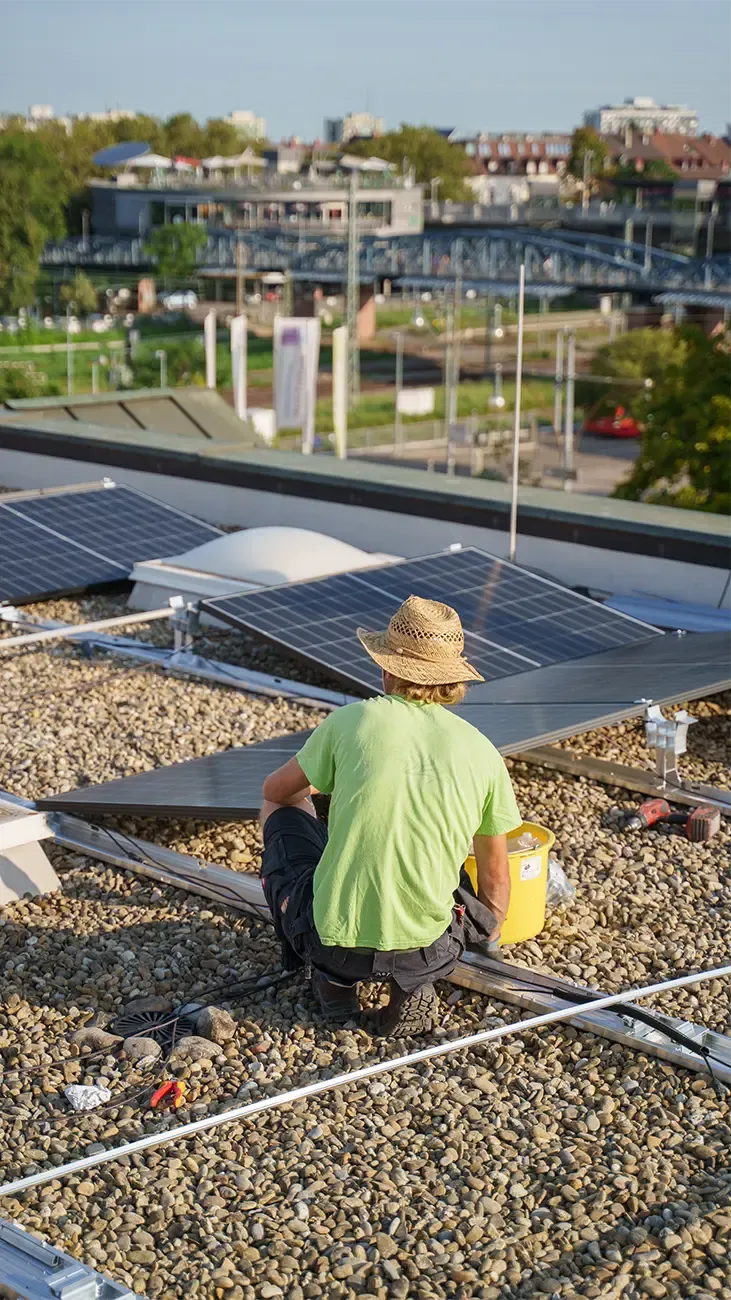 Solartechniker arbeitet an Solarmodulen auf einem Flachdach